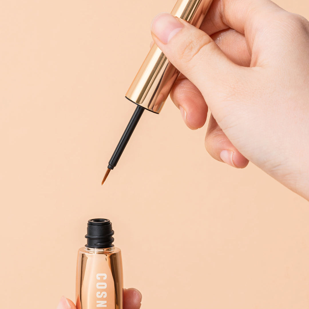 Cosnori Eyelash Serum 100 EX held in hand showing brush applicator