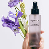 Skybottle Perfumed Hair Body Mist Starry Night 100ml held in hand with flowers
