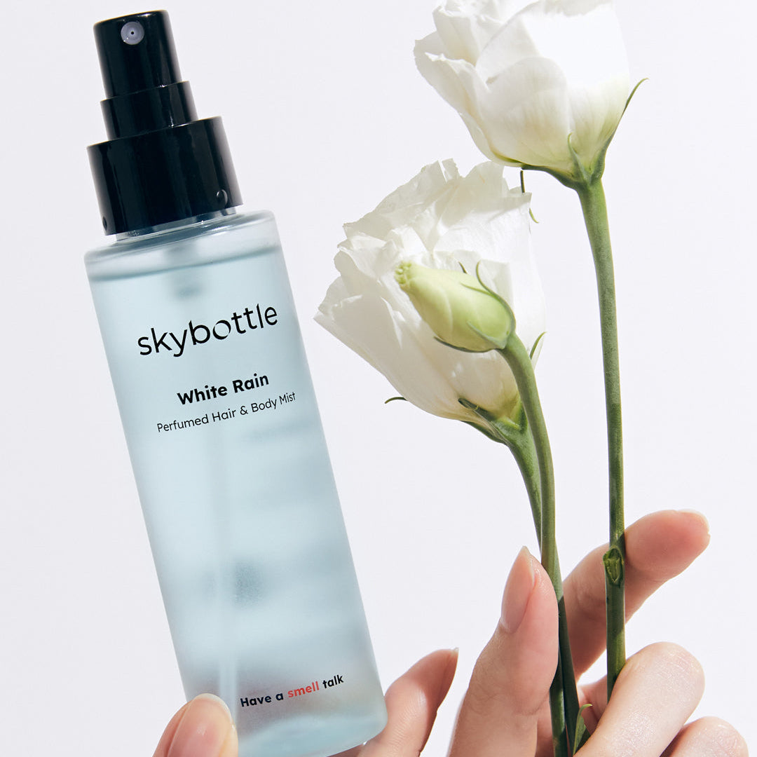 Skybottle Perfumed Hair Body Mist White Rain 100ml held in hand with flowers